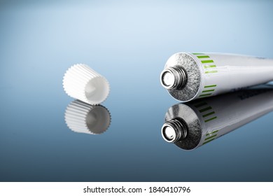 ointment or gel for external use is slightly squeezed out of the tube next to the cap on a gradient background with reflection - Shutterstock ID 1840410796