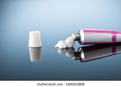ointment or gel for external use is slightly squeezed out of the tube next to the cap on a gradient background with reflection