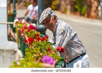 Ojen, Spain - May 22, 2017 : A Senior Gentleman Smiles Looking At Flowers