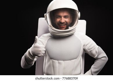 I am ok. Waist up portrait of cheerful spaceman wearing helmet with full armor is standing and looking at camera with joy while showing thumb-up. Isolated background. Cosmonaut concept