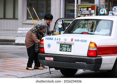 Okinawa, JP - JANUARY 31, 2018: A Friendly Good Female Taking An Old Lady Into The White Taxi.