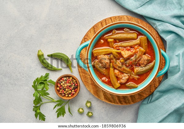 Okra and\
meat stew in a pot. Top view, copy\
space