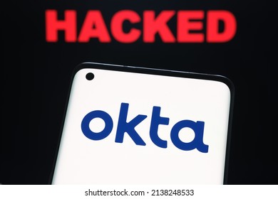 Okta security firm logo seen on smartphone and the word HACKED on blurred background. Concept for hack. Stafford, United Kingdom, March 22, 2022.