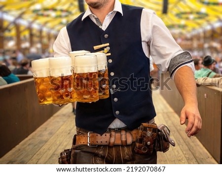 Oktoberfest, Munich. Waiter in traditional Bavarian costume serving beers, close up view. October fest German beer festival.