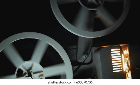 Old 8mm film projector playing in the night. Close-up of a reel with a film. - Powered by Shutterstock