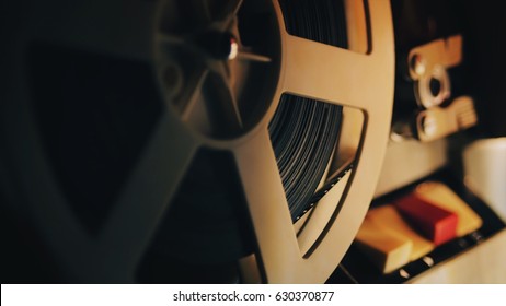 Old 8mm film projector playing in the night. Close-up of a reel with a film.