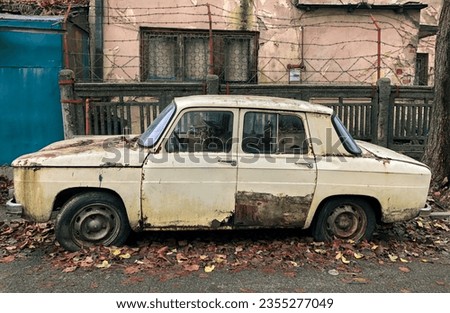 An old abandoned auto car in front of a weathered house