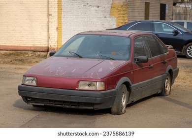 An old abandoned broken car with flat tires on the city parking. The scrap and recycling vehicle. The dusty and rusty machine body and the broken headlight - Powered by Shutterstock