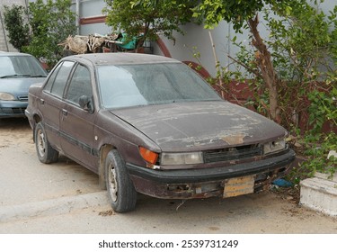An Old Abandoned Car With Rust, Missing Front Grille And Faded Paint Sits By Curb Neglect And Disuse