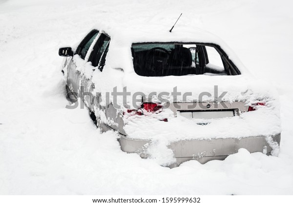 old abandoned car without glass and wheels in the\
snow in the field