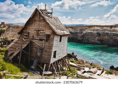 Old abandoned house on the edge of a cliff overlooking the sea and cliffs in the background
