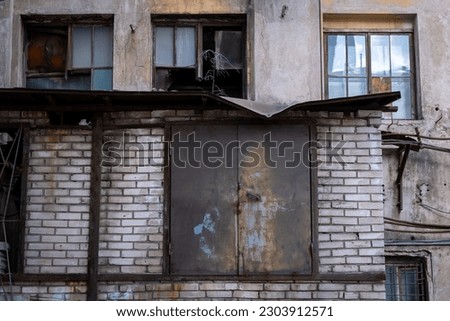 Old abandoned industrial building with broken windows and an iron warehouse door