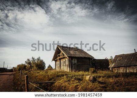 An old, abandoned log house. Deserted village in Russia. A lonely hut without people. Rotten wall construction. Hut against the background of the blue sky. Karelia. Russia. Day.