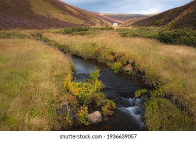 An old abandoned mining site, Lecht Mine and stream in the rolling hills countryside landscape of Cairngorms National Park, in the Scottish Highlands of Scotland.