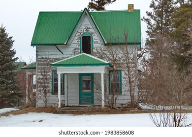 An old abandoned Ontario Cottage style house with a green metal roof.