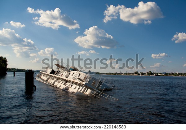 Old and abandoned passenger boat with damaged hull tied at dock half sinking in water