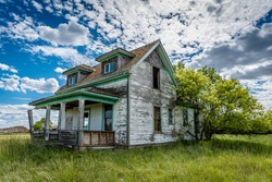 Old, Abandoned, Prairie Farmhouse With Trees, Grass And Blue Sky In Saskatchewan, Canada