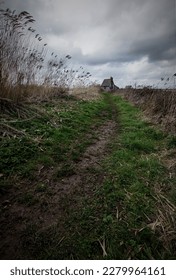 Old abandoned rural ghostly house, isolated at the top of a grassy lane. Creepy looking dwelling. Haunted and sinister, with a long path leading up to the door. Dark and moody. copy space 