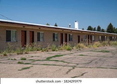 Old, Abandoned Seedy Motorcourt Style Motel, Decays In The Sun. Weeds Overgrowing In The Parking Lot