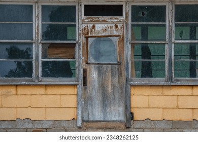 Old abandoned train station with windows and a rustic door.  Yellow walls with a rustic door surrounded by screened windows.   - Powered by Shutterstock