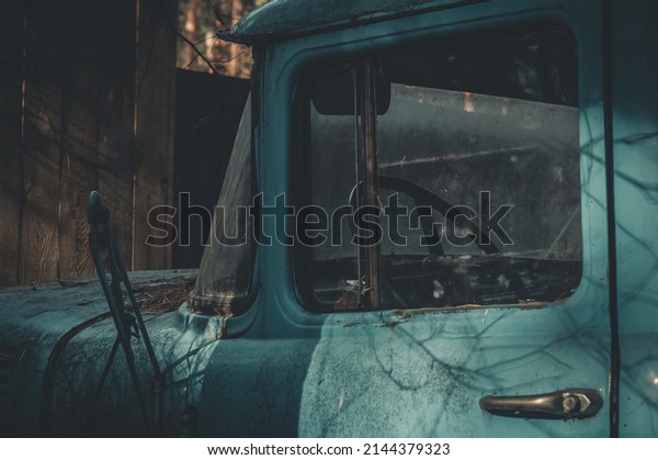 An old abandoned truck. The cab of\
the truck is blue. Car Graveyard. Selective focus,\
grain