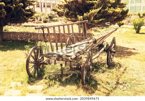 Old abandoned wooden cart in a forest glade in\
the village