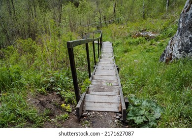 An old abandoned wooden staircase, steps from boards, a descent down the stairs with railings, a park for walking, a landscape in the forest. High quality photo - Shutterstock ID 2171627087