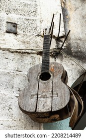 Old Acoustic Guitar Hanging On The Concrete Wall