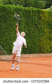 Old Active Man Serving Ball On Tennis Match