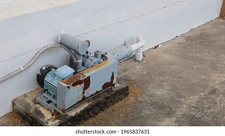 Old aerator beside the wall. Motor and air pump for aerating in dirty and rusty septic sump installed on the side of the building on a cement patio floor with copy area. Selective focus