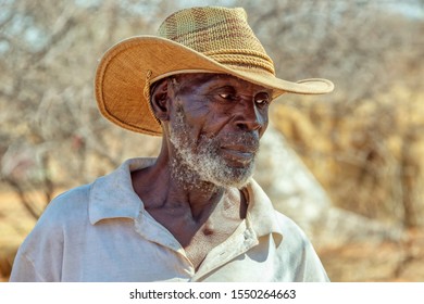 Old African man in a village in Botswana standing in front of a shack in the bush
