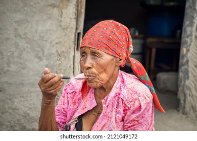 Old African Woman Eating  In Front Of The Outdoor Kitchen In An African Village