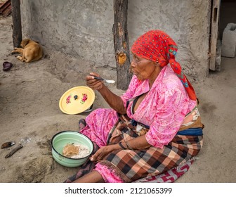 Old African Woman Eating  In Front Of The Outdoor Kitchen In An African Village