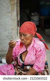 Old African Woman Eating In Front Of The House In An African Village