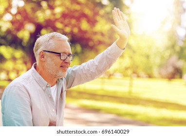 Old Age, Gesture And People Concept - Happy Senior Man In Glasses Waving Hand At Summer Park