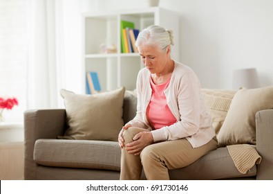 old age, health problem and people concept - senior woman suffering from pain in leg at home