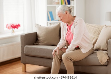 Old Age, Health Problem And People Concept - Senior Woman Suffering From Pain In Leg At Home