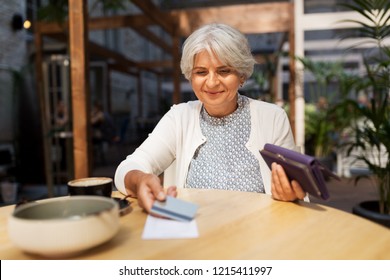 Old Age, Leisure, Payment And Finances Concept - Happy Senior Woman With Credit Card And Wallet Paying Bill For Coffee And Dessert At Street Cafe