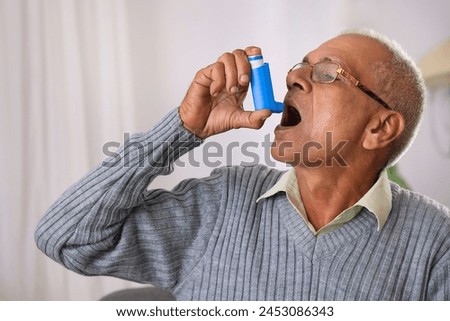 Old age man using her Asthma Inhaler at home