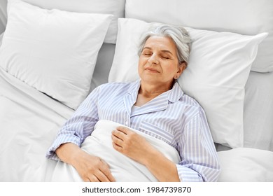 Old Age And People Concept - Happy Senior Woman Sleeping In Bed At Home Bedroom