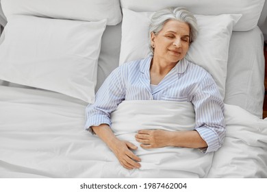 Old Age And People Concept - Happy Senior Woman Sleeping In Bed At Home Bedroom