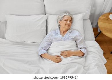 Old Age And People Concept - Happy Senior Woman Sleeping In Bed At Home Bedroom