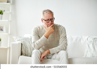 Old Age, Problem And People Concept -  Senior Man In Glasses Thinking And Sitting On Sofa At Home