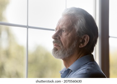 Old age problems. Worried concerned hoary elderly male pensioner stand alone look through window. Distressed confused aged grandfather feel lonely abandoned think of solitude on retirement. Copy space - Powered by Shutterstock