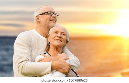 Old Age, Tourism, Travel And People Concept - Happy Senior Couple Over Sunset Background