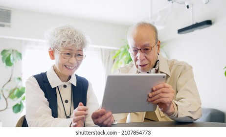 Old Aged Asian Couple Using A Tablet PC.