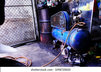 Old Air Compressor Blue Color In Garage .Has Oil Stain And Junks On The Floor.