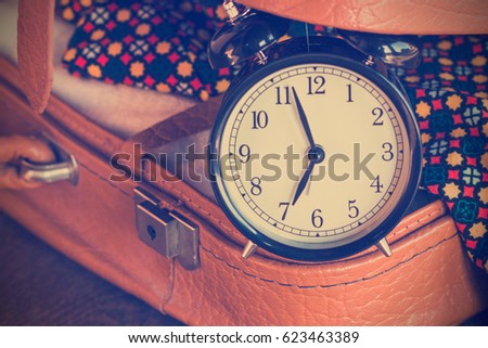 Old alarm clock in suitcase close up toned