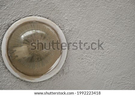 Old and already used ancient style yellow color lamp and on the concrete and plaster wall