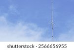 An old amateur radio antenna standing tall against a background of sky and clouds.